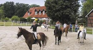 un grupo de gente montando caballos en un campo de tierra en Heidehotel Gut Landliebe Restaurant Montags Ruhetag!, en Hermannsburg