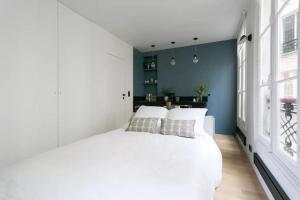 パリにあるJoie Paris St Germain des Prés - Jardin Luxembourgの白いベッドと青い壁が備わるベッドルーム1室が備わります。