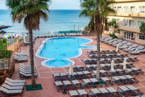 een uitzicht op een zwembad met stoelen en de oceaan bij Hotel Cala Font in Salou
