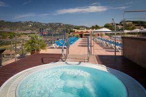 een hot tub op een terras met stoelen en een zwembad bij htop Calella Palace & SPA 4Sup #htopFun in Calella