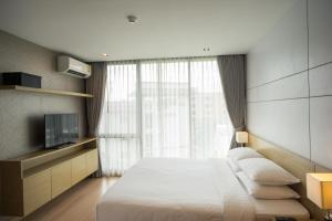 een slaapkamer met een groot bed en een televisie bij Sanae' Hotel Nimman in Chiang Mai