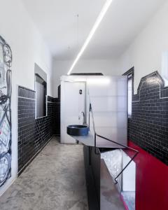 baño con lavabo y azulejos negros en Box Art Hotel - La Torre en Collado Mediano