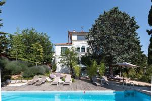 a swimming pool with chairs and a house in the background at Box Art Hotel - La Torre in Collado Mediano