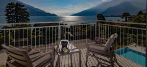 ein Balkon mit zwei Stühlen und Blick aufs Wasser in der Unterkunft Hotel Domaso in Domaso