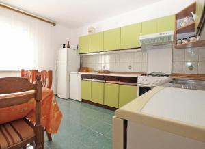 cocina con armarios verdes y nevera blanca en Apartment 1686, en Pula