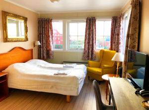 a hotel room with a bed and a chair and a desk at Røst Bryggehotell in Røst