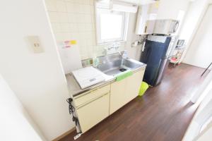 a small kitchen with a sink and a refrigerator at Luxes Hiroshima4F ラクセス ヒロシマ4F in Hiroshima