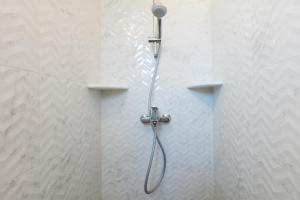 a shower with a shower head on a wall at Panorama Apartments updated with infinity pool in Agios Nikolaos