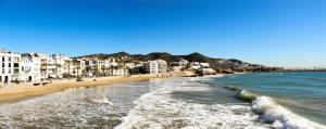 シッチェスにあるSitges Ático 2 min a Playa San Sebastíanの建物と海を望むビーチの景色を望めます。