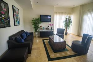 a living room with a couch and chairs and a tv at Acqua Residences 503 in Jacó