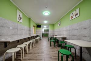 une salle à manger avec des murs et des tables verts et des tabourets verts dans l'établissement Ostriv Hostel, à Lviv