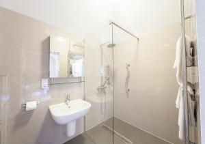 a white bathroom with a sink and a shower at Heacham Manor Hotel in Hunstanton