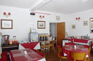 ein Restaurant mit roten Tischen und Stühlen in einem Zimmer in der Unterkunft Bayside in Paignton