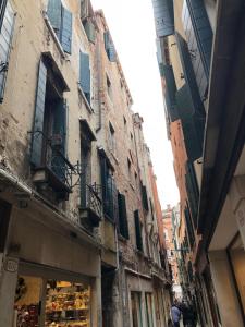 eine schmale Gasse mit Gebäuden in einer Stadt mit einem Geschäft in der Unterkunft Mansardina San Marco in Venedig