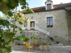 een stenen huis met een tafel en stoelen ervoor bij L'Hirondelle in Lantilly