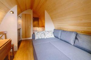 una sala de estar con sofá en una habitación con techos de madera en Campion Glamping Pod, en Cheltenham