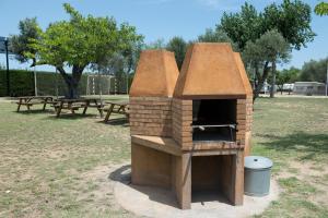 un horno de ladrillo en un parque con una mesa de picnic en Camping Relax Ge, en Mont-ras