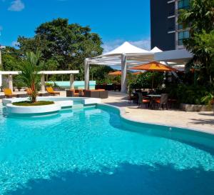 een zwembad naast een resort met tafels en parasols bij Summit Rainforest Golf Resort & All Inclusive in Paraíso
