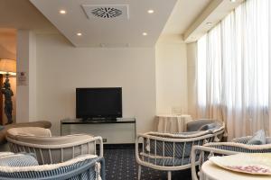 sala de estar con sillas y TV de pantalla plana en Hotel Anthony, en Lido di Jesolo