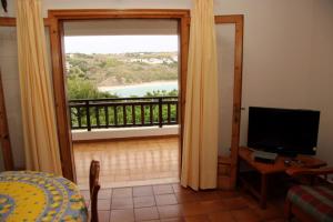 um quarto com uma porta que abre para uma varanda com uma televisão em Apartamentos Arco Iris em Punta Grossa