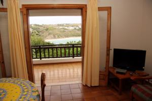 Habitación con puerta que da a un balcón con TV. en Apartamentos Arco Iris, en Punta Grossa
