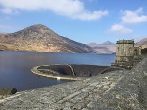 a dam on a lake with mountains in the background at A fourteen in Kilkeel
