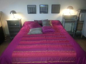 a large bed with a purple blanket on it at Tres agreable maison au calme dans la pinede in Lacanau-Océan