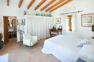 um quarto com uma cama branca e uma cadeira em Owl Booking Villa Coloma - Luxury Retreat with Huge Pool em Port de Pollença