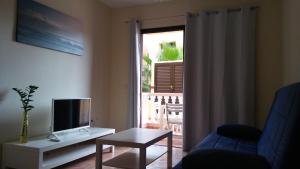 een woonkamer met een tv en een bank en een tafel bij APARTAMENTOS EL CIENO in La Playa Calera
