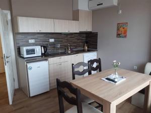 a kitchen with a wooden table and a microwave at CAPUCCINO GUEST APARTMENTS - FREE PARKING and Wi-Fi in Sunny Beach
