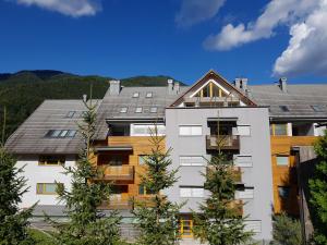 a house with a roof with trees in front of it at Yellow apartma Kranjska Gora in Kranjska Gora