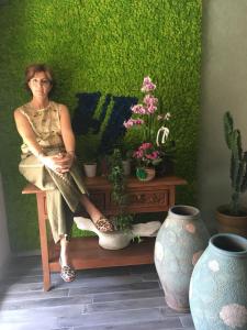 a woman sitting on a bench next to plants at Hotel Lucerna in Castiglione della Pescaia