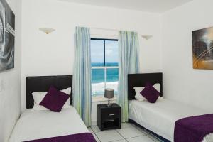 two beds in a room with a view of the ocean at Santorini - Perissa 22 in Ballito