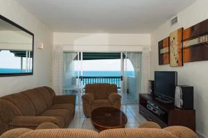 a living room with a couch and a tv at Santorini - Perissa 22 in Ballito