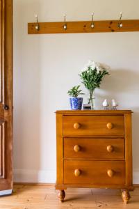 a wooden dresser with a vase of flowers on it at 20 Hill Avenue Bed & Breakfast in Keith