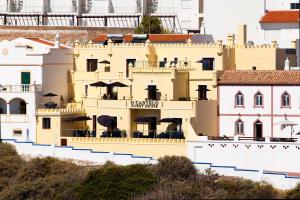 um grande edifício amarelo com guarda-chuvas em cima em Castelo Guest House em Carvoeiro