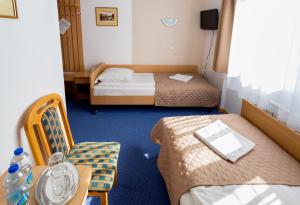 a small room with two beds and a table and chairs at Kompleks Hotelowy Logos in Augustów