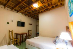 a room with two beds and a table and a television at Posada Los Tajibos in Puerto Iguazú