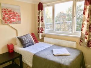 a small bedroom with a bed and two windows at London Deluxe Loft Apartment with Shower in London