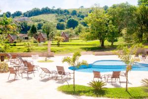 a patio with chairs and a swimming pool at Pousada Villa Di Carpi in Monte Sião