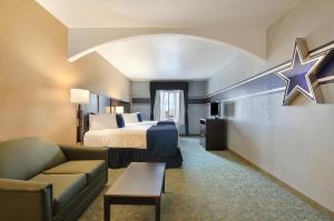a hotel room with a bed and a couch at Ramada by Wyndham South Waco in Hewitt +52 photos