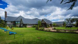 马查科斯Oldonyo Sapuk Resort的一栋带院子的房子，院子前面有一头牛。