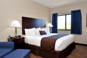 um quarto de hotel com uma cama grande e uma cadeira azul em Cobblestone Inn & Suites - Manning em Manning