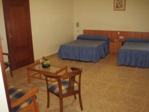 a room with a bed, chair, table and a television at Apartahotel Los Hermanos in Ocaña
