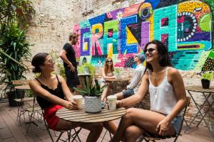 three women sitting at a table in front of a mural at Sant Jordi Hostels Gracia in Barcelona