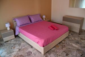 a bedroom with a bed with pink sheets and purple pillows at La Contessa Apartment in Palermo