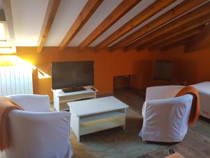 uma sala de estar com duas cadeiras brancas e uma televisão em Posada La Rivera De Escalante em Escalante