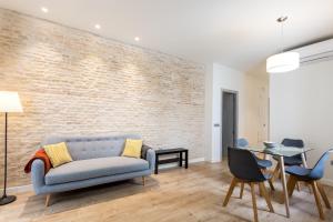 a living room with a blue couch and a brick wall at Apartamentos Lanza in Seville