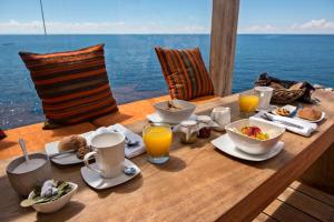 a table with food and orange juice on top of the ocean at Amantica Lodge in Ocosuyo