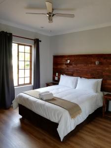 a bedroom with a large white bed with a wooden headboard at La Vue Guesthouse in Lanseria